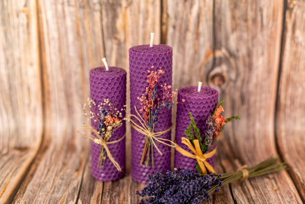 Purple honey candles handmade from natural wax on a background of wooden boards. Elements from natural materials. Christmas or New Years composition. Photo for postcards. - Photo, Image