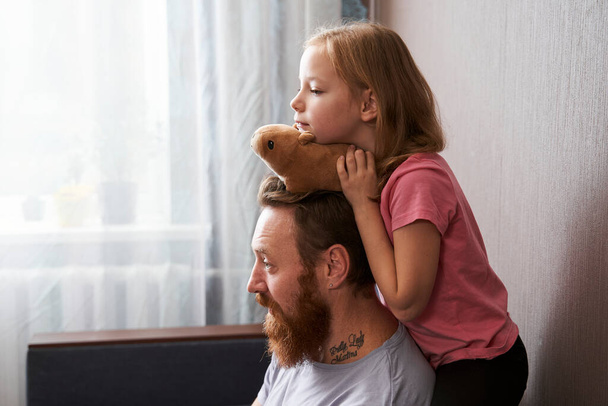 Girl embracing her daddy with her soft toy - Foto, afbeelding
