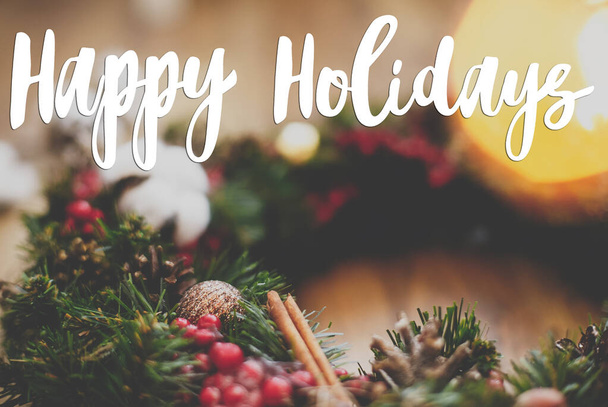 Kellemes ünnepeket üdvözlőlap. Boldog ünnepeket szöveg kézzel írt karácsonyi koszorú pamut, vörös bogyók, díszek és kúp - Fotó, kép