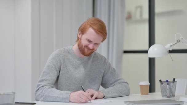 Pelirroja hombre incapaz de escribir en el papel en el trabajo  - Imágenes, Vídeo