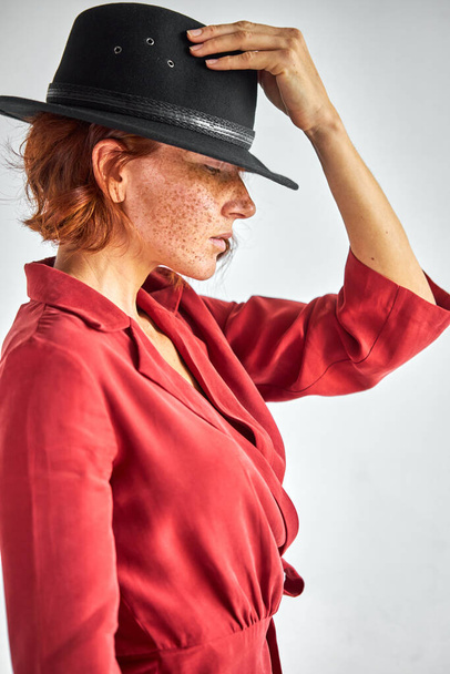 portrait of confident elegant lady in dress and hat looking down posing - Zdjęcie, obraz