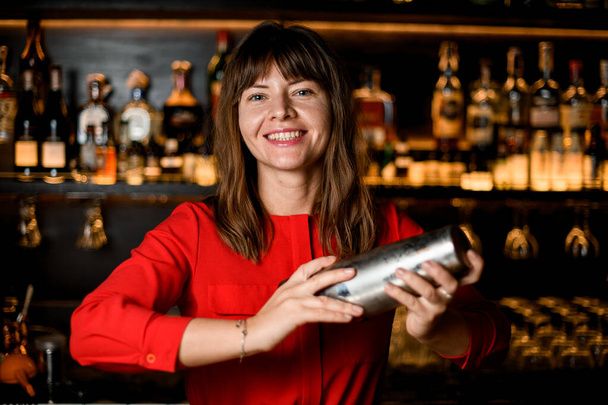 portrait of beautiful smiling woman bartender with steel shaker in her hands - Фото, зображення