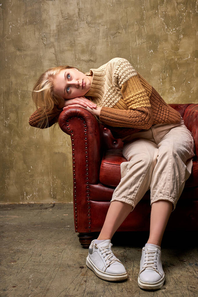 dreamy blonde female sits dreaming on sofa - 写真・画像