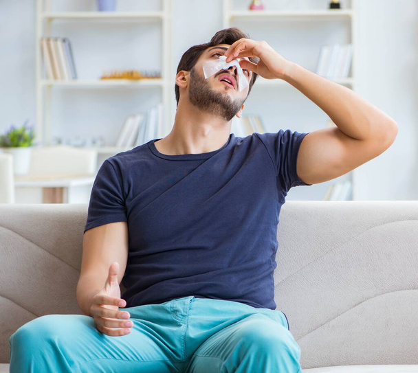 Młody mężczyzna odzyskuje zdrowie w domu po operacji plastycznej nosa - Zdjęcie, obraz