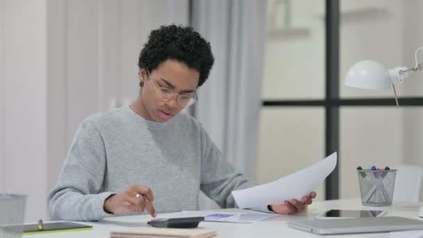 Mujer africana usando calculadora mientras escribe en papel  - Metraje, vídeo
