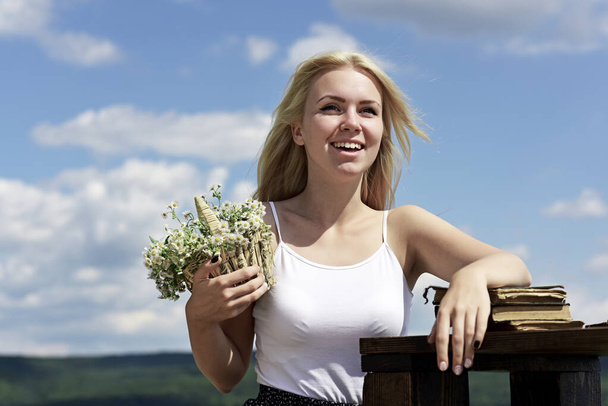 Portrait of a beautiful blonde young girl in the spring. Young woman holding bouquet of wildflowers in the nature. Concept of spring. - Foto, Bild