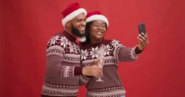Рождественский праздник на расстоянии. Счастливая африканская американская пара с шампанским разговаривает с друзьями в видеочате - Кадры, видео