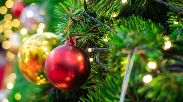 Κοντινό πλάνο πολύχρωμων μπαλών στο χριστουγεννιάτικο δέντρο. Ο Μπόκε Γκάρλαντ στο βάθος. Νέο Έτος έννοια. - Φωτογραφία, εικόνα