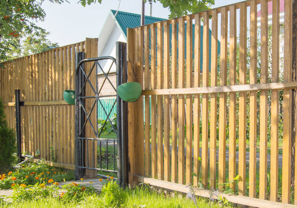 金属ゲート付きの新しい木製のピケフェンス、カントリーハウスのセキュリティと保護の概念. - 写真・画像