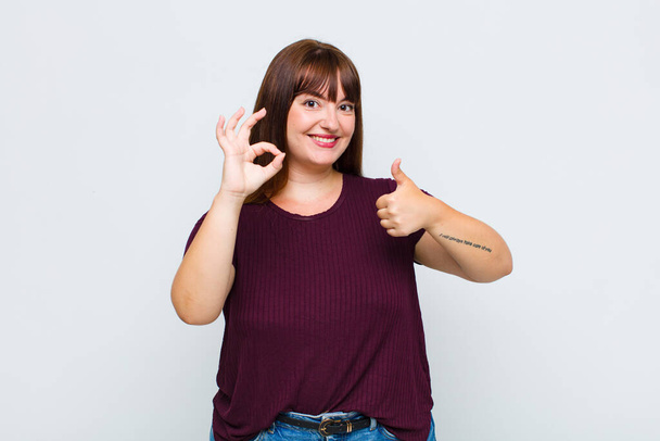 overweight woman feeling happy, amazed, satisfied and surprised, showing okay and thumbs up gestures, smiling - Photo, image