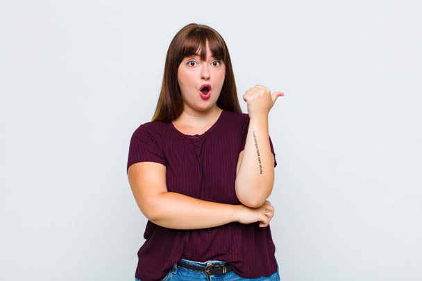 overweight woman looking astonished in disbelief, pointing at object on the side and saying wow, unbelievable - Photo, image