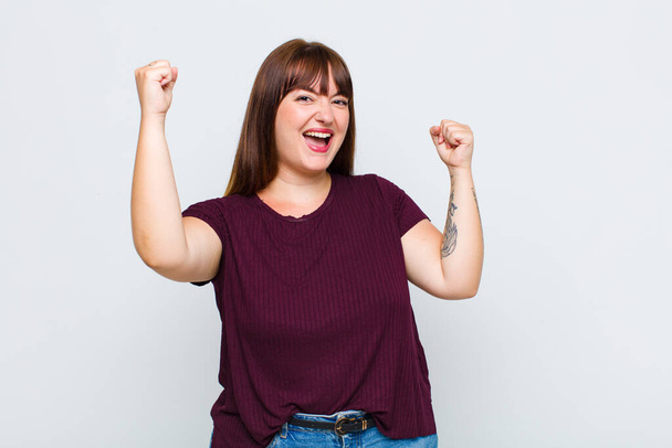 mulher com sobrepeso gritando triunfalmente, parecendo animado, feliz e surpreso vencedor, comemorando - Foto, Imagem