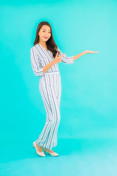 Portrait beautiful young asian woman smile in action on blue isolated background - 写真・画像