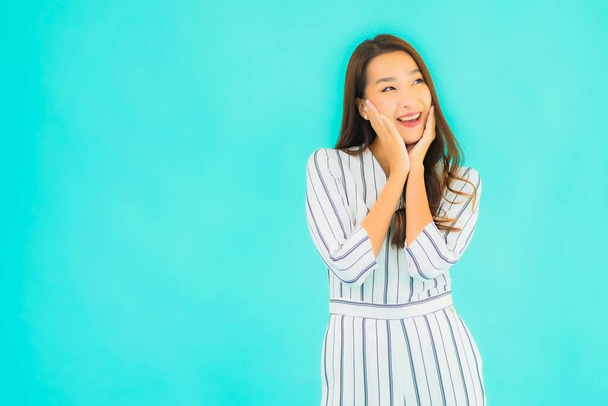 Porträt schöne junge asiatische Frau lächeln in Aktion auf blauem Hintergrund - Foto, Bild