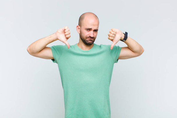 bald man looking sad, disappointed or angry, showing thumbs down in disagreement, feeling frustrated - Foto, Imagen