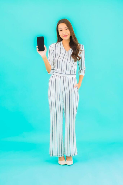 Porträt schöne junge asiatische Frau verwenden Smartphone auf blauem Hintergrund - Foto, Bild