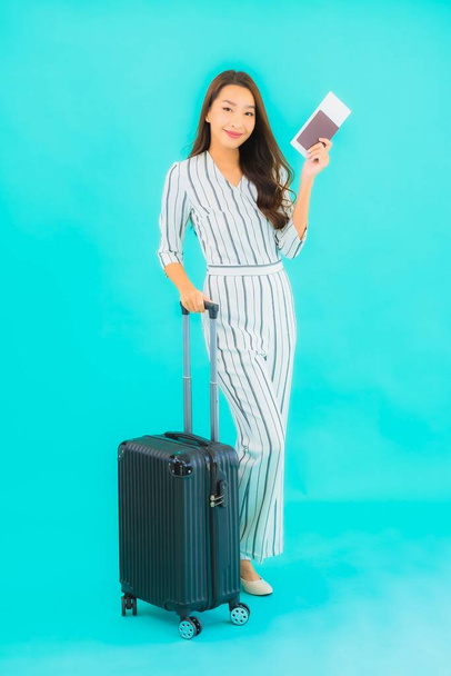 Portret pięknej młodej azjatyckiej kobiety z paszportem bagażowym i kartą pokładową gotowej do podróży na niebieskim tle - Zdjęcie, obraz
