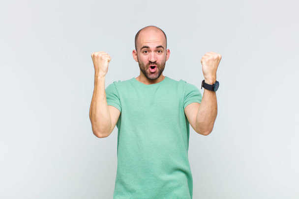 bald man celebrating an unbelievable success like a winner, looking excited and happy saying take that! - Foto, Imagen