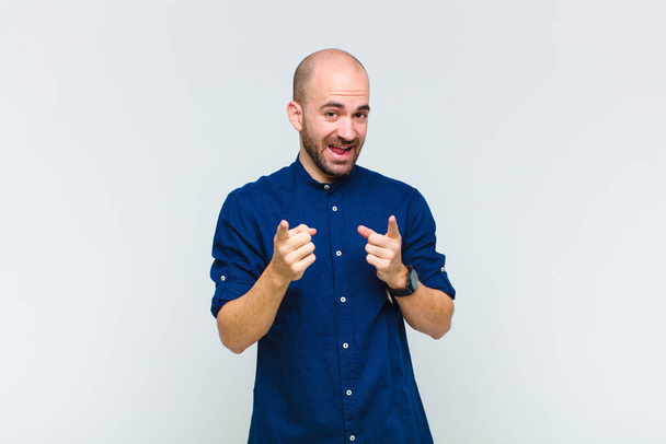 bald man smiling with a positive, successful, happy attitude pointing to the camera, making gun sign with hands - 写真・画像