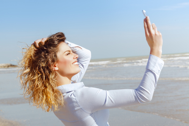 jonge mooie blonde vrouw nemen een selfie op het strand - Foto, afbeelding