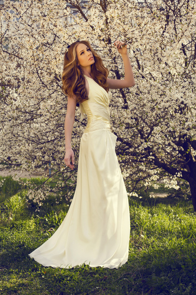 hermosa chica con el pelo rojo posando en el parque de flores de primavera
 - Foto, Imagen