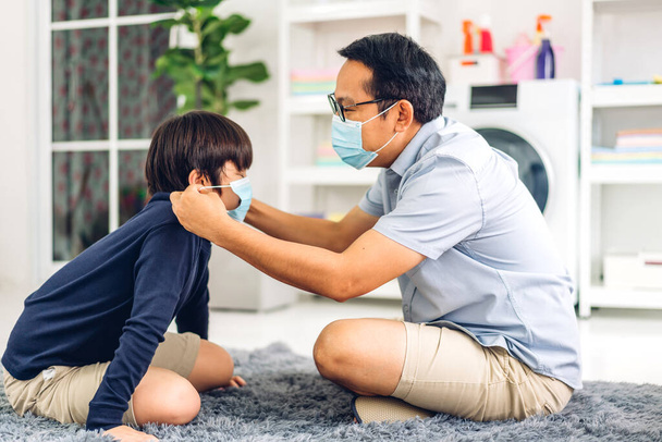 Koronavirüs için karantinadaki küçük Asyalı çocuk için koruyucu maske takan mutlu Asyalı bir babanın portresi. - Fotoğraf, Görsel