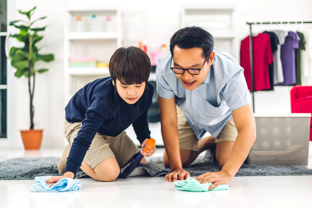 Father teaching asian kid little boy son use disinfectant spray bottle cleaning and washing floor wiping dust with rags while cleaning house together at home - Foto, imagen