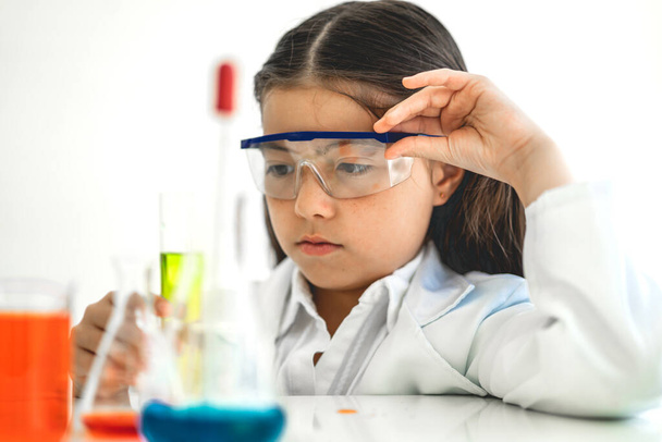 Aranyos kislány diák tanulási kutatás és csinál egy kémiai kísérlet, miközben elemzése és keverése folyadék üveg tudományos osztály az asztalon.Oktatás és a tudomány koncepció - Fotó, kép