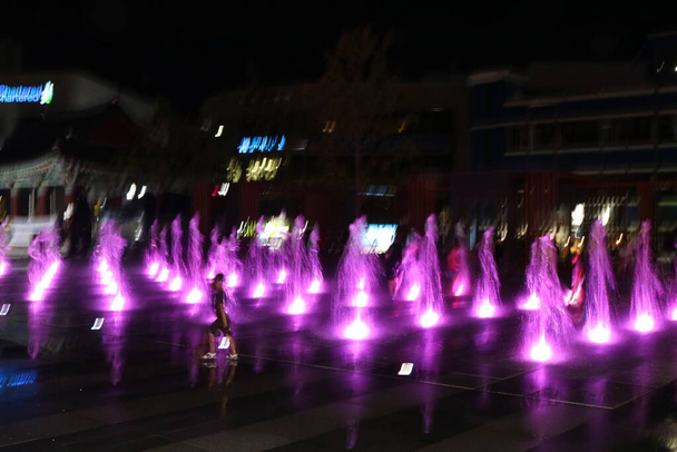 Belle et colorée fontaine à eau légère en vue de la nuit. forme d'eau colorée sur fontaine avec fond noir. - Photo, image