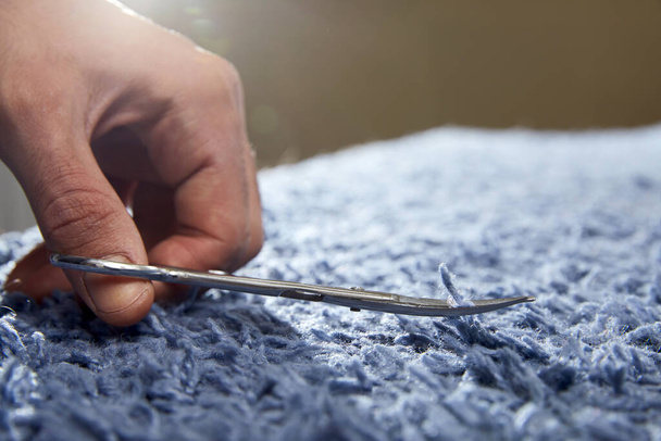 Zbliżenie dłoni odcięcie sznurka na dywanie nożyczkami. Usługi sprzątania dywanów - Zdjęcie, obraz