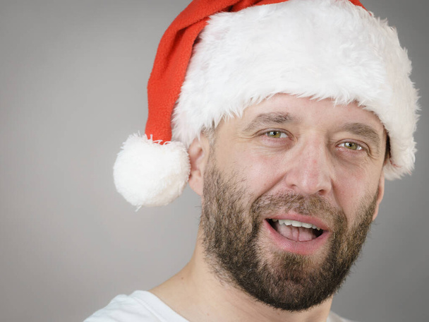 Bearded man wearing santa claus hat portrait, on grey. Christmes time. - Photo, Image