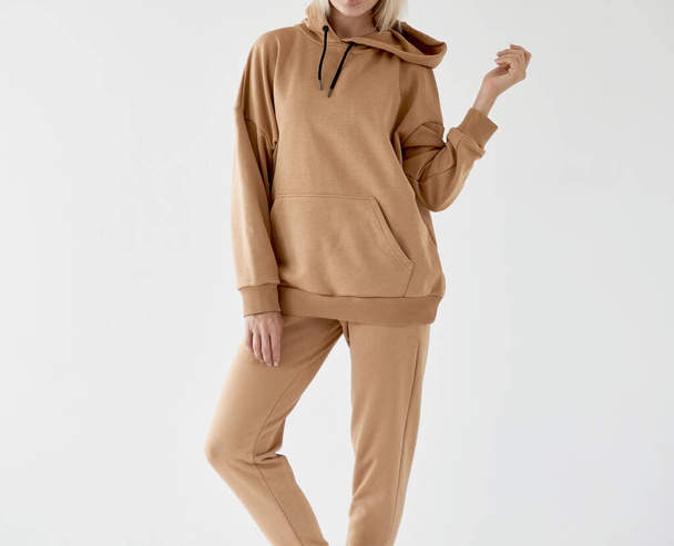 girl wears light brown hoodie and pants. isolated photo of women wearing nude color fleece textile outfit. - Foto, Imagem
