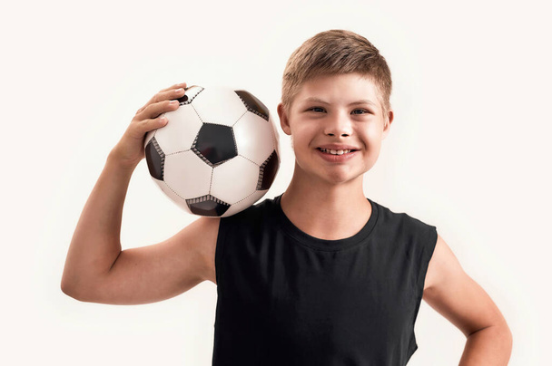 Happy disabled boy with Down syndrome smiling at camera while posing with football isolated over white background - Фото, зображення