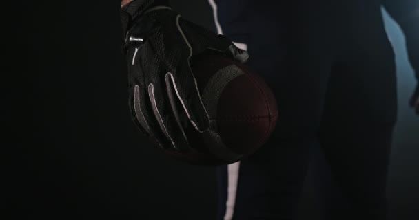 Amerikaanse voetbal sporter speler met een bal op zwarte achtergrond close-up - Video