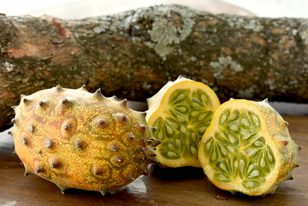 Die Kiwano oder gehörnte Melone afrikanische Frucht auf Holztisch und einem Ast im Hintergrund - Foto, Bild