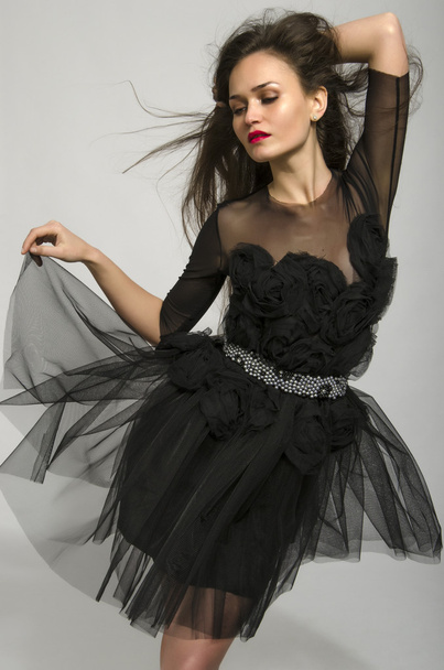 Beautiful brunette woman wearing a black dress with flowers and dancing - Zdjęcie, obraz