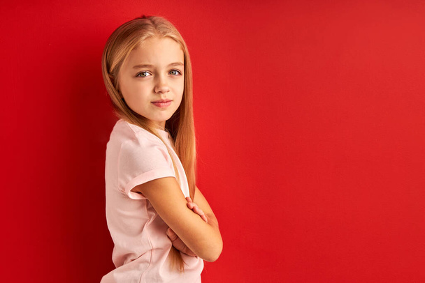 shy confident caucasian child girl isolated over red studio background - Foto, immagini