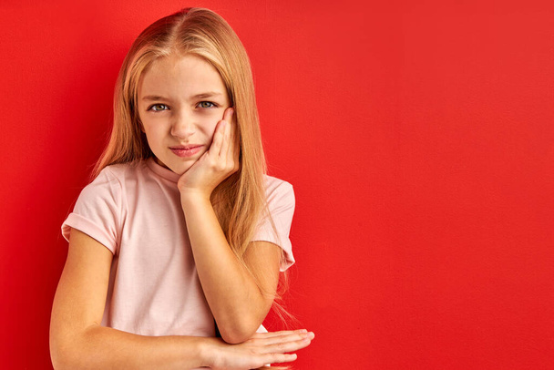 depressed and worry child girl with sad expression isolated on red background - Foto, afbeelding