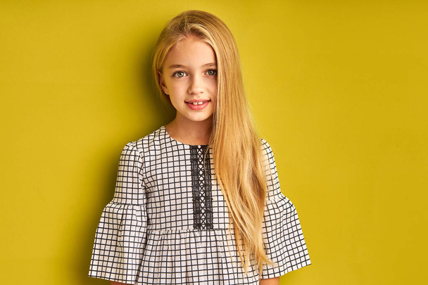 amazing kid girl with long hair in blouse looks at camera smiling - Fotó, kép