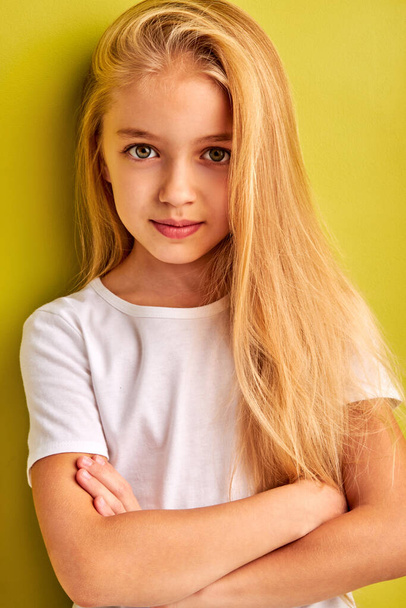 nice caucasian little girl with long blond hair isolated on green background - Foto, Bild
