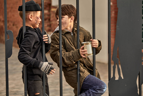 two homeless kids ask for money through bars - Valokuva, kuva