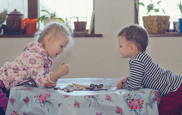 Niño y niña jugando a las damas
 - Foto, Imagen