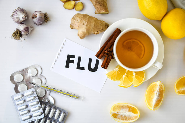 FLU - written on piece of paper among the products for the treatment of common cold - lemon, ginger, chamomile tea. Vitamin natural drink. Cinnamon anise star. Natural medicine vs conventional medicine - Foto, imagen