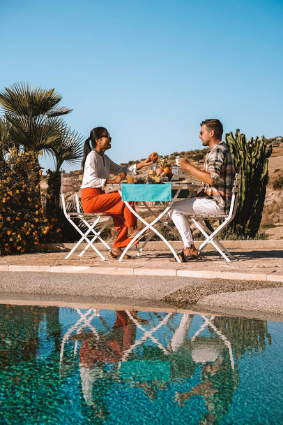 casal tomando café da manhã no jardim olhando para fora sobre as colinas da Sicília, homens e mulheres de meia idade em férias tomando café da manhã - Foto, Imagem