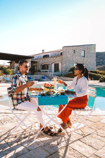 pareja desayunando en el jardín con vistas a las colinas de Sicilia, hombres y mujeres de mediana edad en vacaciones desayunando - Foto, Imagen