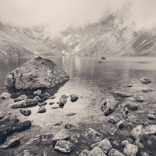 High Tatras 'taki sisli dağlarda bir göl. Slovakya. Orta Avrupa. Sisteki dağların arka planına karşı kristal berrak bir göl manzarası. - Fotoğraf, Görsel