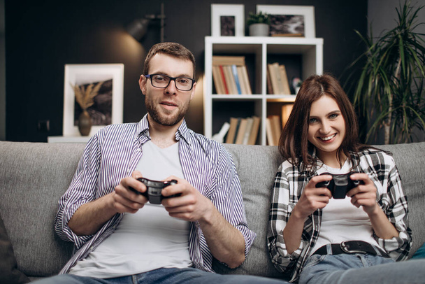 Νεαρό ζευγάρι που χρησιμοποιεί joysticks για να παίζει παιχνίδια - Φωτογραφία, εικόνα