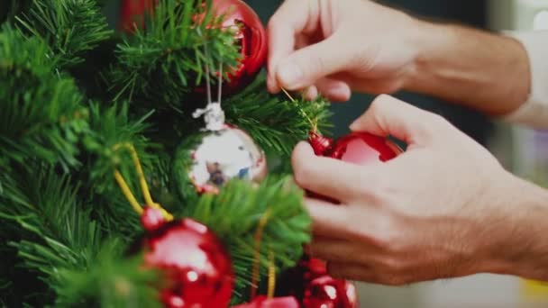 Lähikuva kädet Aasian mies tilalla punainen pallo Joulu koristella joulukuusi juhlii uutta vuotta. Joulujuhla käsite. - Materiaali, video