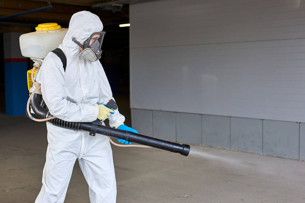 sanitation worker in hazmat suit working with pressure washer or sanitizer - Foto, immagini