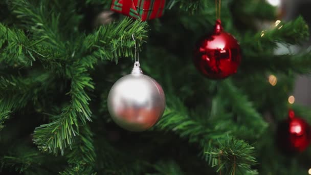 La cámara panorámica derecha enfoca las bolas de Navidad y los adornos de luces El árbol de Navidad celebra el nuevo año en la sala de estar en casa. Concepto de celebración de Navidad. - Metraje, vídeo